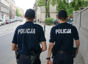 Na zdjęciu dwój policjantów w patrolu pieszym idących ulicą.