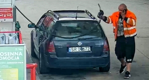 Na zdjęciu mężczyzna zatankował volkswagena i odstawia pistolet do tankowania.
