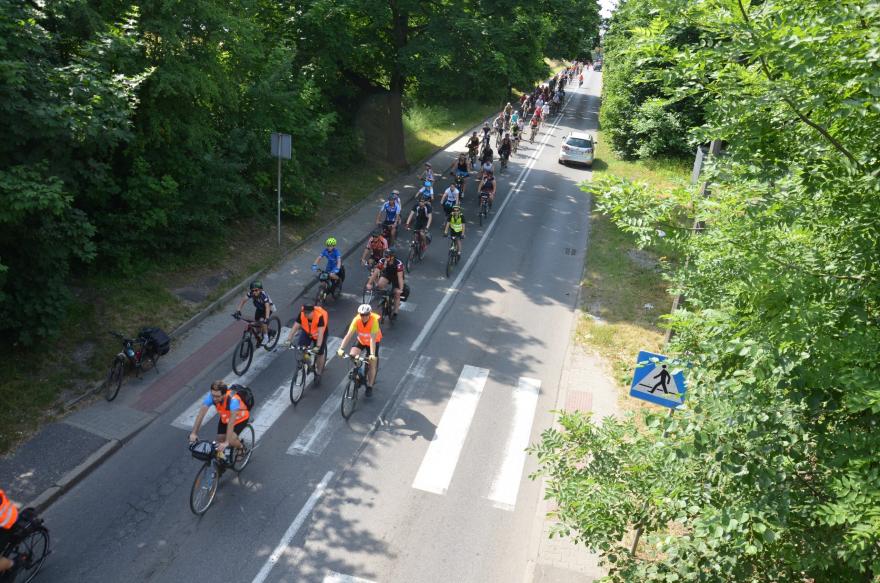 Peleton rowerzystów jadący miejska ulicą.