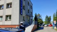 budynek komisariatu w Knurowie, przed nim policjant w mundurze galowym