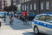 Radiowóz a za nim czterech rowerzystów.