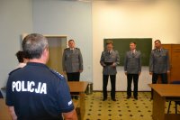 Na zdjęciu po lewej policjant . Centralnie czterech policjantów w umundurowaniu służbowym.