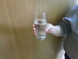 Uchylone drzwi i mieszkaniec podaje szklankę wody.