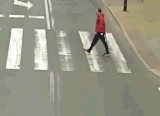 Mężczyzna w czerwonej kurtce na oznakowanym przejściu dla pieszych.