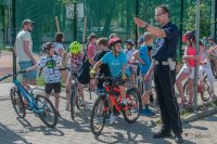 Policjant tłumaczy coś dzieciom na rowerach