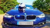 Nieoznakowany radiowóz BMW i kask motocyklowy na jego masce.