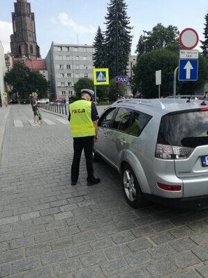 Umundurowany policjant kontroluje pojazd terenowy.