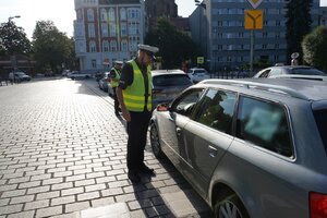 Umundurowany policjant kontroluje kierowcę.