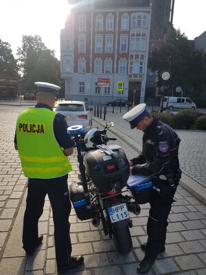 Umundurowani policjanci kontrolują kierowcę. Policjant motocyklista.