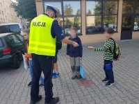 Policjant rozdaje odblaski dzieciom.