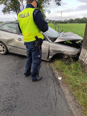 Policjant stoi przy rozbitym aucie.