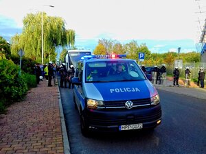 Policyjny radiowóz typu bus i policjanci zabezpieczający mecz w tle