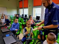 Policjant rozdaje odblaski dzieciom.