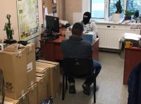 policjant w kominiarce przesłuchuje podejrzanego przy biurku