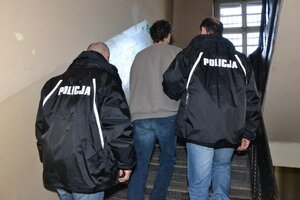 dwaj policjanci prowadzą zatrzymanego
