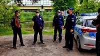 Policjanci i strażnicy miejscy na brzegu zbiornika wodnego.