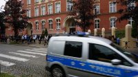 Policyjny radiowóz przejeżdża przed szkołą.