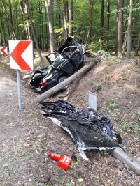 Rów - pobocze drogi asfaltowej. Po prawej stronie wrak samochodu marki BMW.