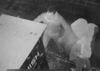 Dwaj mężczyźni przed automatem sprzedażowym. Jeden kopie w szybę automatu.
