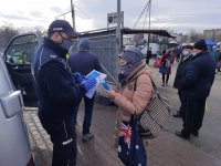 Policjant rozmawia z kobietą przed wejsciem na targowisko miejskie.