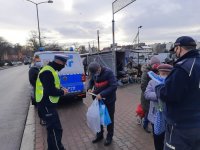 Policjant rozmawia z mężczyzną przy wejsciu na targ miejski.