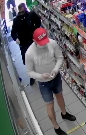 Dwaj meżczyźni między regałami w sklepie drogeryjnym.