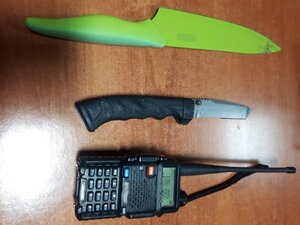 Od góry dwa noże, na dole kadru radiotelefon ręczny.