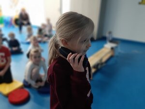 Dziewczynka trzyma przy uchu słuchawke - telefonuje.