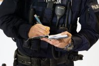 Policjant pisze coś w notatniku służbowym.