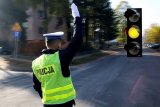 Policjant ruchu drogowego na skrzyżowaniu, ma uniesiona prawą rękę