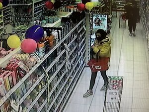 Kobieta w kurtce z kapturem i koszykiem w sklepie drogeryjnym.