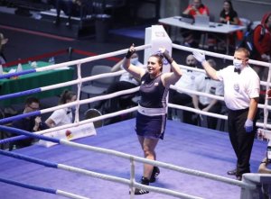 Ring bokserski a na nim Lidia Fidura z uniesionymi w geście zwycięstwa rękoma. Obok sędzia pięściarski.