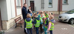 Dziedziniec pyskowickiego komisariatu. Policjant rozdaje dzieciom breloczki.