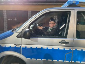 Chłopiec w policyjnej furażerce za kierownica radiowozu.