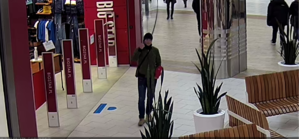 Młody mężczyzna rozmawiający przez telefon, znajduje się w holu hipermarketu.