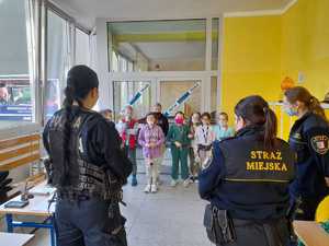 Policjantka i strażnicy miejscy rozmawiają z uczniami.