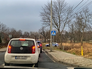 Widok samochodu marki skoda stojącego w kolejce do badań kierowców na stan trzeźwości. Po prawej widać radiowóz policyjny.