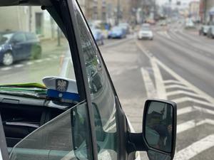 Furgon radiowóz, na podszybiu czapka policjanta drogówki, w tle ruchliwa ulic.