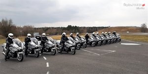 Kilkunastu policyjnych motocyklistów na torze wyścigowym - pozują do zdjęcia ustawieni w szeregu