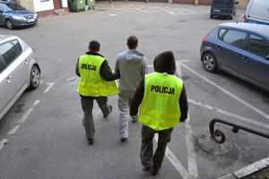 Dwóch policjantów prowadzi zatrzymanego