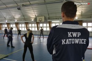 Instruktor patrzy na osoby ćwiczące w hali sportowej