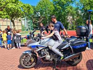 Policyjny motocykl, na nim dziecko i stojący obok policjant..