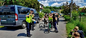 Policjant ruchu drogowego i grupa młodzieży zdająca egzamin na kartę rowerową.