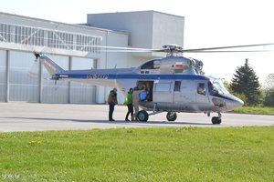 Policyjny helikopter na gliwickim lotnisku. Osoby wyładowują specjalny ładunek