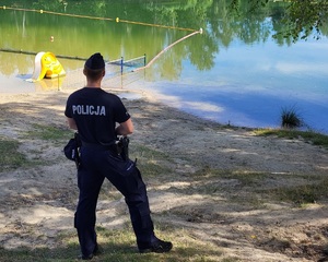 Policjant stojący na brzegu jeziora.