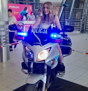 Nastolatka siedzi na motocyklu policyjnym.