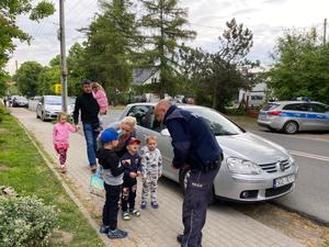 policjant rozmawia z dziećmi przed szkołą.