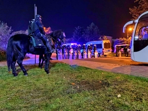 Zabezpieczenie meczu, po lewej dwaj policjanci na koniach, w tyle policjanci w szyku z tarczami.