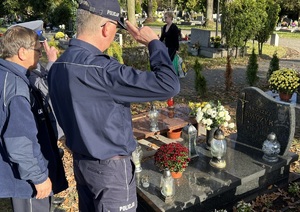 Salutujacy komendant stojący przed nagrobkiem zmarłego policjanta.