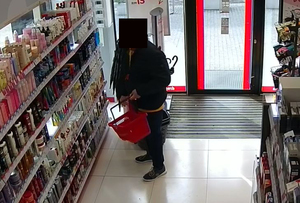 Mężczyzna z zamazaną komputerowo twarzą wchodzący do sklepu - drogerii